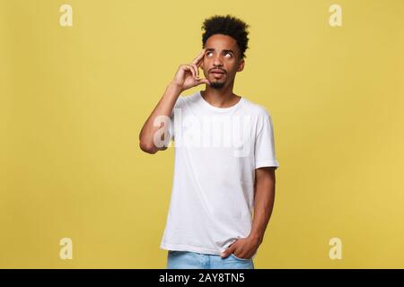 Bild von nachdenklichen jungen afrikanischen Mann im weißen T-Shirt, die auf gelben Hintergrund isoliert gekleidet. Stockfoto