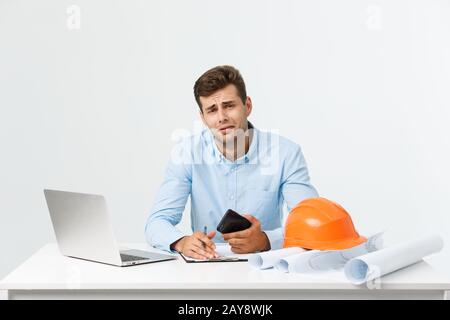 Ein ernsthafter Mann, der auf der Baustelle sitzt, ist Geschäftsmann oder Ingenieur. Mutiger Mann mittleren Alters sitzt mit traurig, ernst und depressiv Stockfoto