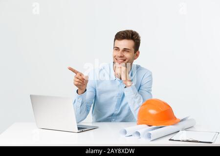 Portrait von jungen männlichen Innenarchitekt oder Ingenieur lächelnd, während er auf seinem Tisch. Stockfoto