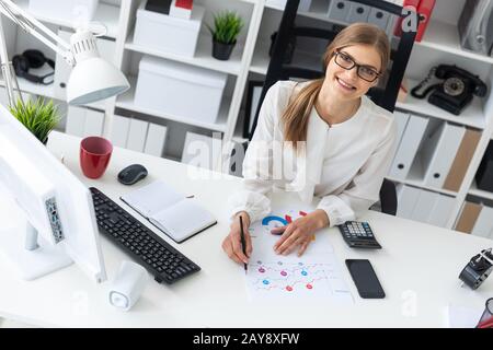 Ein junges Mädchen sitzt an einem Computer Schreibtisch im Büro und hält einen Bleistift in der Hand. Stockfoto