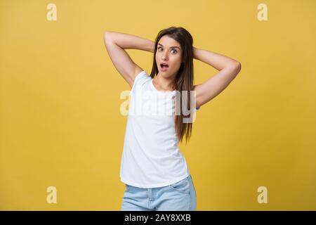 Wunderschönes, halblängerliches Porträt isoliert auf gelbem Studiobackgroud. Die junge, gefühlvolle lächelnde und überraschte Frau steht Stockfoto