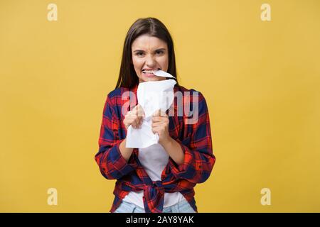 Aggressive jungen kaukasischen Frau tränen Vertrag oder weißes Blatt Papier. Auf gelben Hintergrund. Stockfoto