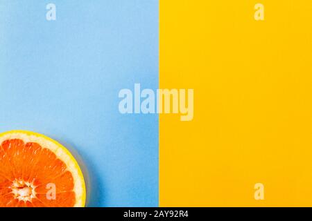 Einzelne Grapefruit Slice Nahaufnahme auf blauem und gelbem Hintergrund Stockfoto