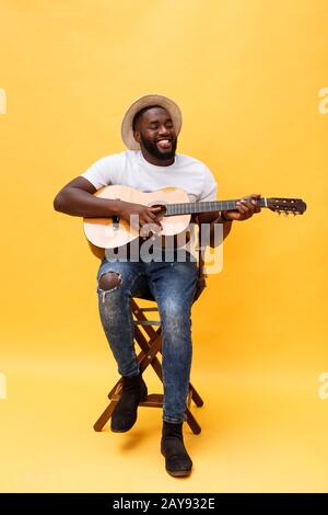 In voller Länge Foto von Angeregten künstlerische Mann, der seine Gitarre spielen in ungezwungener Suite. Auf gelben Hintergrund. Stockfoto