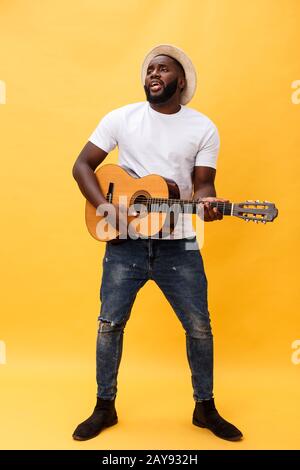 In voller Länge Foto von Angeregten künstlerische Mann, der seine Gitarre spielen in ungezwungener Suite. Auf gelben Hintergrund. Stockfoto