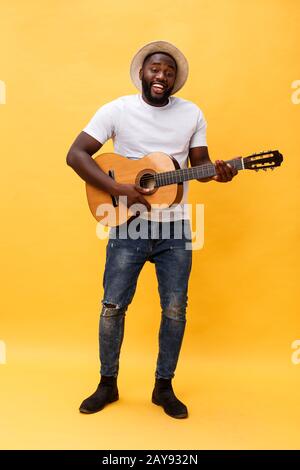 In voller Länge Foto von Angeregten künstlerische Mann, der seine Gitarre spielen in ungezwungener Suite. Auf gelben Hintergrund. Stockfoto