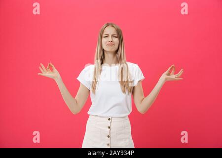 Blonde beauiful junge Frau macht Mudra-Zeichen, entspannt sich nach hartem Arbeitstag, hält die Augen geschlossen, übt Yoga gegen den rosafarbenen Rücken Stockfoto