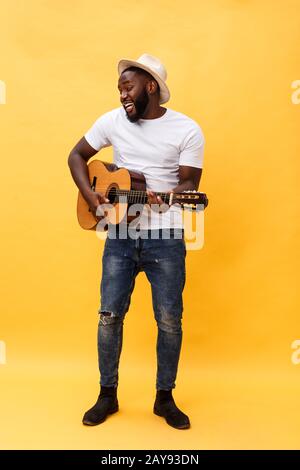 In voller Länge Foto von Angeregten künstlerische Mann, der seine Gitarre spielen. Auf gelben Hintergrund. Stockfoto