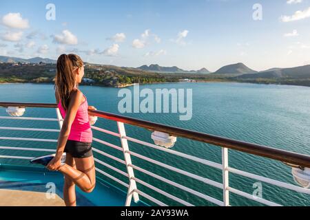 Training des Fitness-Läufers Dehnen der Beine Aufwärmstrecken, bevor er auf den Schienen des Kreuzfahrtschiffs läuft. Frau mit Blick vom Deck des Anrufhafens Castries in St. Lucia. Stockfoto