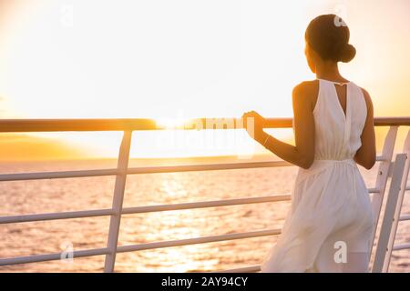 Kreuzfahrtschiff-Urlaub Frau genießt Sonnenuntergang auf Reisen auf See. Elegante, glückliche Frau in weißem Kleid mit Blick auf das Meer, entspannend auf einem luxuriösen Kreuzfahrtschiff. Stockfoto