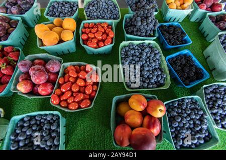 In der Nähe von oben aus Karton und Plastikkartons mit Obst und Gemüse. Lokaler Lebensmittelmarkt, gute Auswahl an Artikeln im Verkauf. Tomaten unter den Früchten. Stockfoto