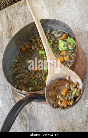 Gekochte Linsen mit Karotten in einem Kupfertopf Stockfoto