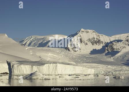 Berge und Gletscher an der Küste der Antarktis und Eisberge im Meer in der Nähe von Es Stockfoto