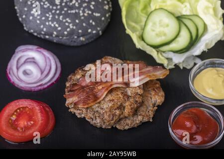 Zutaten für einen Hamburger auf schwarzem Schiefer Stockfoto