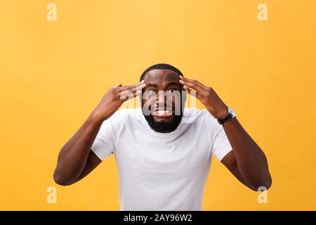 Portrait der afrikanischen amerikanischen Mann mit Händen in Schock und Ungläubigkeit. Auf gelben Hintergrund. Stockfoto