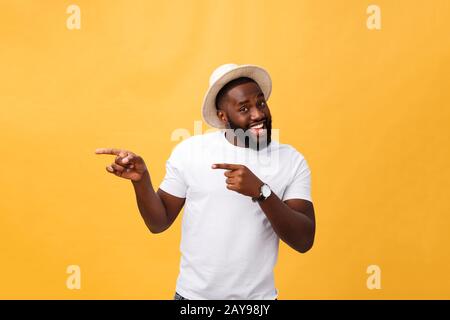 Lustiger junger afrikanischer Kunde lächelt glücklich und zeigt seine Zeigefinger auf die Kamera, als ob er Sie wählt und zu großem sal einlädt Stockfoto