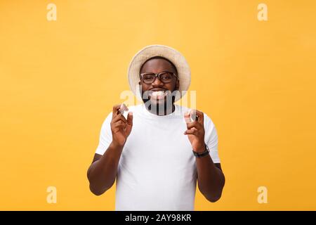 Junger afroamerikanischer Mann über isoliertem Hintergrund lächelnde Kreuzungsfinger mit Hoffnung und geschlossenen Augen. Glück und abergläubisch c Stockfoto