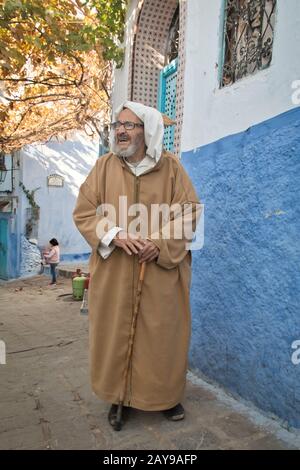 Chefchaouen, Marokko - 11. Dezember 2016: Älterer Mann mit traditioneller marokkanischer Kleidung, der durch die Medina von Chaouen in Marokko geht Stockfoto