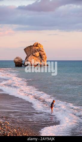 Ein Junge spielt am Strand an den Felsen Petra tou Romiou, in Paphos, Zypern. Stockfoto