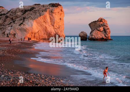 Ein Junge spielt am Strand an den Felsen Petra tou Romiou, in Paphos, Zypern. Stockfoto