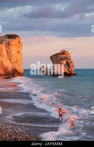 Ein Junge spielt am Strand an den Felsen Petra tou Romiou, in Paphos, Zypern. Stockfoto