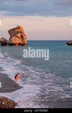 Ein Junge spielt am Strand an den Felsen Petra tou Romiou, in Paphos, Zypern. Stockfoto