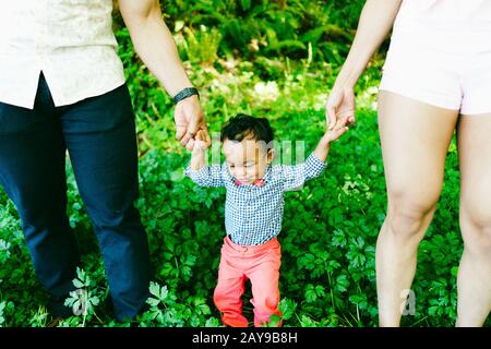 Zugeschnittene Ansicht eines Vaters und einer Mutter, die die Hände ihres Sohnes halten Stockfoto
