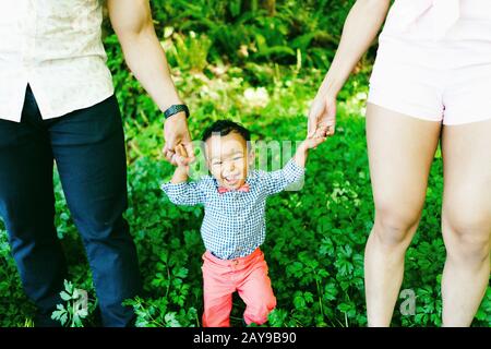 Zugeschnittene Ansicht eines lächelnden Jungen, der die Hände seiner Eltern hält Stockfoto