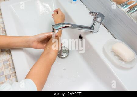 Das Kind wäscht seine Hände bis zu den Ellbogen im Waschbecken im Bad Stockfoto