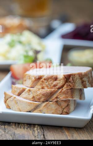 Bayerische Leberkäese auf dunklem Holz Stockfoto