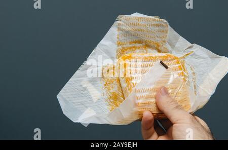Französische Küche Küchenchef männliche Hand hält vor reinem grauen Hintergrund traditionellen französischen Käse in Papierverpackungen Stockfoto