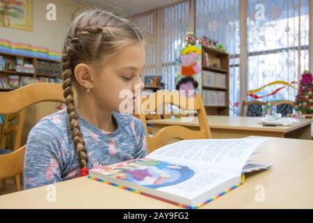 Ein Mädchen von zehn Jahre alt ist, ein Buch zu lesen in der Bibliothek Stockfoto