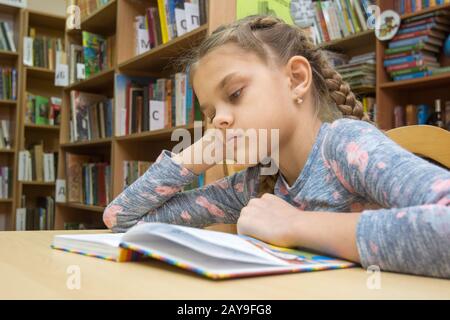Ein Mädchen von zehn Jahre alt ist, ein Buch zu lesen im Lesesaal Stockfoto
