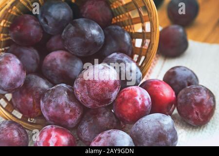 Große reife Pflaumen in einem Weidenkorb. Stockfoto