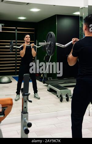 Der junge Mann macht Bizeps mit der z-Bar im Fitnessstudio Stockfoto