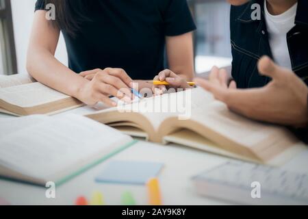 Lern-, Bildungs- und Schulkonzept. Junge Frau und Mann, die zu einem Test oder einer Prüfung studieren. Tutorenbücher mit Freunden. Der Campus junger Studenten hilft Frie Stockfoto