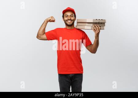 Lieferkonzept - Portrait Des Starken afroamerikanischen Lieferers, der seinen Muskel mit Pizzaschachtel zeigt. Isoliert auf Grau Stockfoto