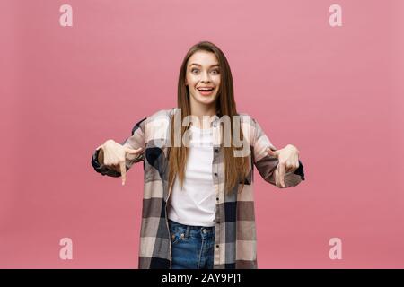 Nette junge Frau weist einen Finger weg über rosa Hintergrund isolieren. Kopieren Sie Platz. Stockfoto