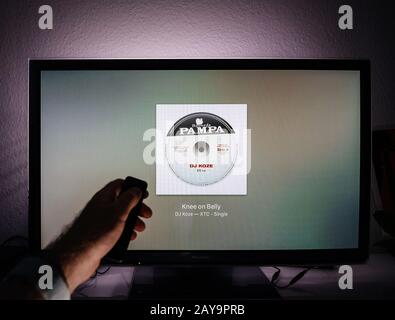 Paris, Frankreich - Ca. 2019: Mann surft mit Remote Apple TV Menü auf Panasonic Plasma tv Wohnzimmer Ladenachricht des Apple Music Streaming-Service Dj Koze neue Single Stockfoto