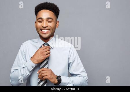 Geschäftskonzept - Glückliche zuversichtlich professionelle afrikanische amerikanische Geschäftsmann über grauer Hintergrund posiert. Stockfoto