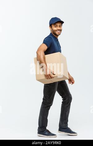 Lieferkonzept - Portrait Of Happy African American Delivery man in Blue Cloth Walking, um dem Kunden ein Paketpaket zu schicken. Isol Stockfoto