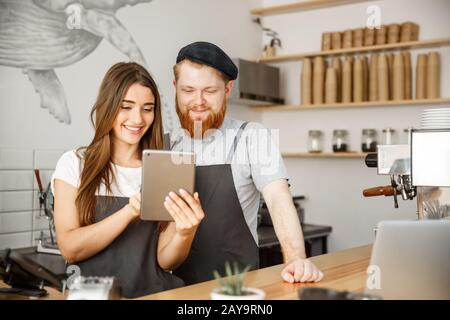 Kaffee Geschäftskonzept - Zufrieden und lächeln Besitzer paar Blick auf Tablet Bestellungen in der modernen Coffee Shop online Stockfoto