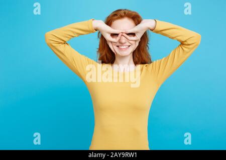 Fun and People Konzept - Headshot Portrait of Happy Ingwer Red Hair Girl with freckles Smiling and Making Finger Glasses. Pastell Stockfoto