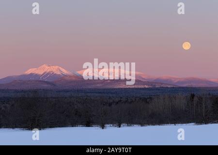 Katahdin und Vollmond bei Sonnenaufgang im Winter. Stockfoto