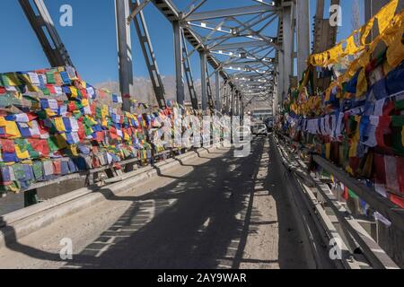 Überqueren der Chuckhot Rd Brücke mit Gebetsfahnen und Schatten, Leh, Ladakh, Indien Stockfoto