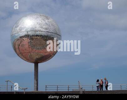 Eine Gruppe von Frauen stand in der Nähe des riesigen Glitterballs an der blackpool-promenade mit blauem Himmel Stockfoto