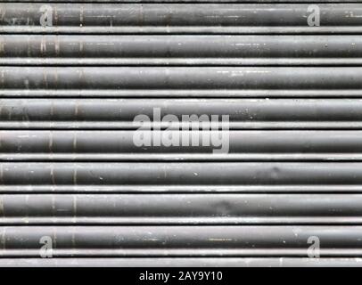 Schmutzige alte graue bunte horizontale geschlossene Rollläden aus Stahl Stockfoto