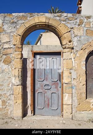 Eine alte Holztür in einem Bogenrahmen in einer alten Steinmauer an einer sonnigen Straße in nikosia zypern Stockfoto