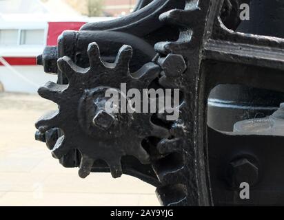 Eine Nahaufnahme der alten abgenutzten schwarz lackierten großen Zahnräder mit Zahnradzähnen an veralteten Industriemaschinen Stockfoto