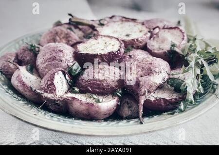 Radieschen mit grünen Zwiebeln auf einem Teller gebacken Stockfoto